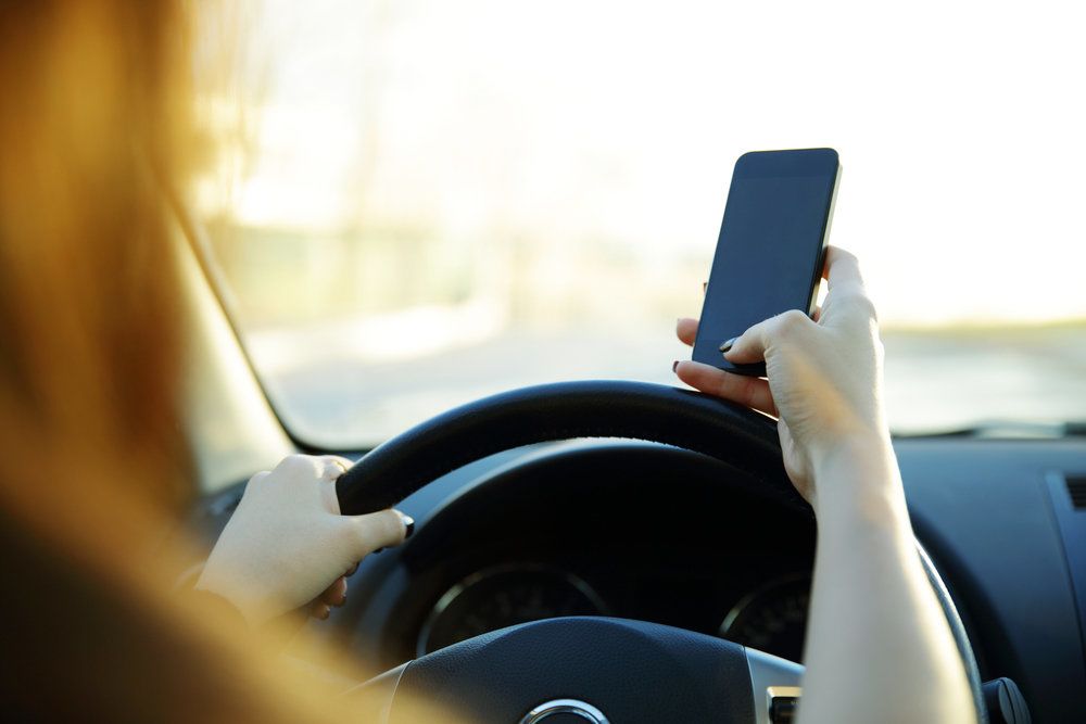 A woman using a cellphone while driving a car