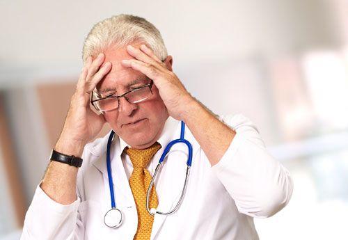 Doctor holding head in hands